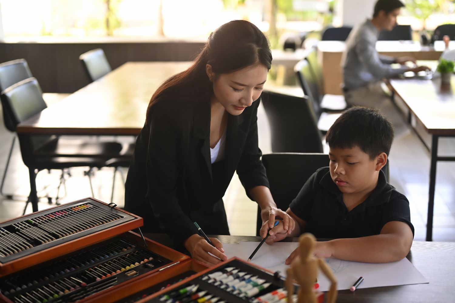 Teacher helping child student with art